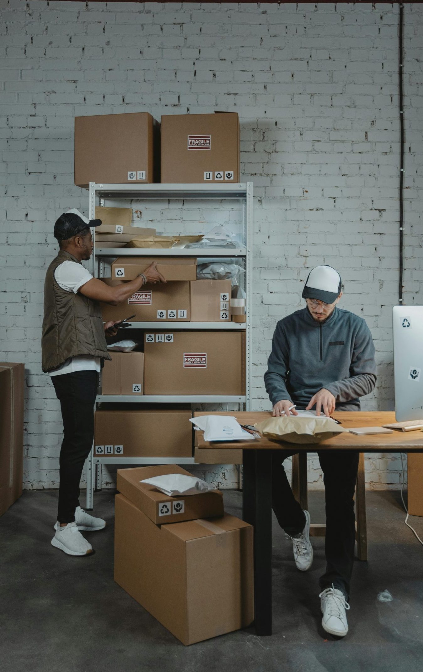 Two male workers organizing and packing boxes in a warehouse setting.